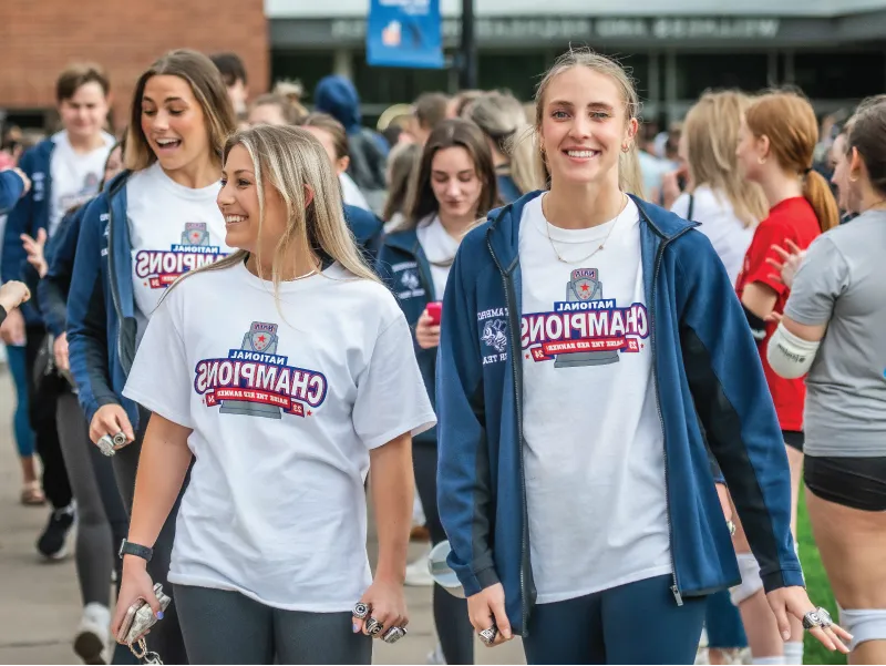 Two cheer team champions walking outdoors, smiling.